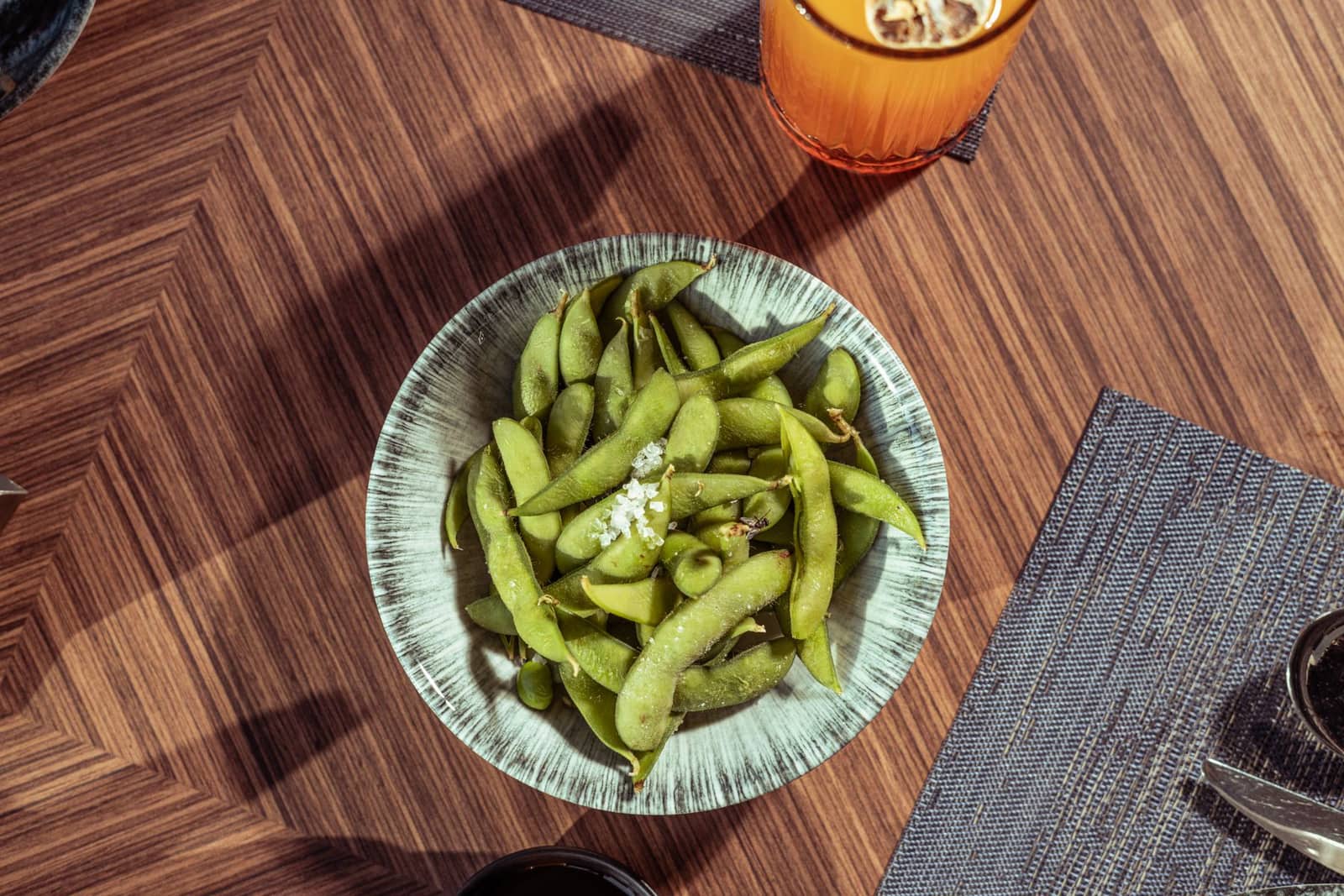 Bol d'edamame frais légèrement salés, posé sur une table en bois claire